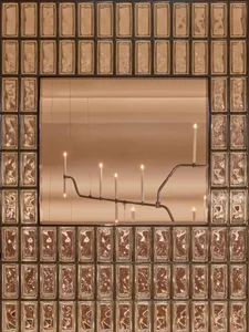 A sophisticated dining space with a large mirror, gold frame, and multiple lit candles creating a warm and inviting atmosphere