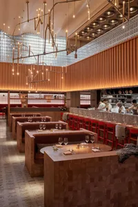 Warm and inviting restaurant interior with wooden floors and walls, featuring dining tables, chairs, wine glasses, and bottles in a comfortable and welcoming environment