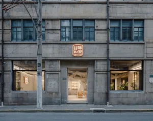 A traditional Asian building with a stone facade, surrounded by potted plants and outdoor seating areas