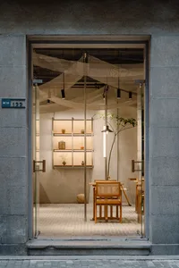擁有座椅、餐桌與盆栽植物的展廳，大片窗戶帶來自然光線環繞