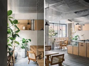 Modern restaurant interior with wood flooring, glass walls, and natural light, featuring a dining area, bar, and potted plants
