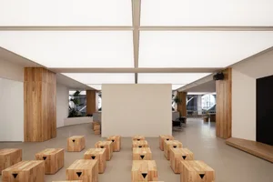 Empty room with a white wall, wooden tables, and a large window, conveying a minimalist and clean atmosphere with a focus on functionality