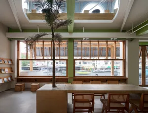 Bright and inviting restaurant interior with green walls, wooden tables, chairs, and benches, and natural light from multiple windows
