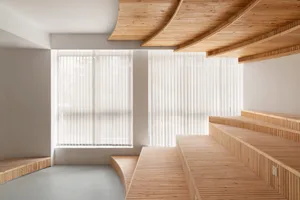 A calm and inviting room with a wooden bench in front of a window, surrounded by two windows and wooden elements