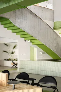 Open living space with a green and white staircase, two chairs, and potted plants