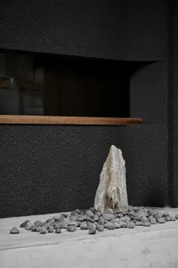 A room with a large rock in the center, surrounded by a black wall, with no other objects or people visible