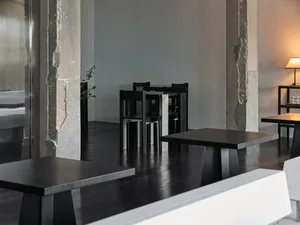A clean and well-organized restaurant with multiple dining tables and chairs, surrounded by white walls and ready for customers