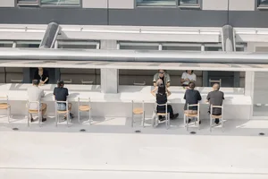 A casual dining area with multiple tables and chairs, featuring a social atmosphere with people gathered to enjoy meals together