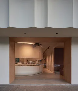 A restaurant interior with a circular dining area, curved wall, and chairs around a large dining table, creating an inviting atmosphere