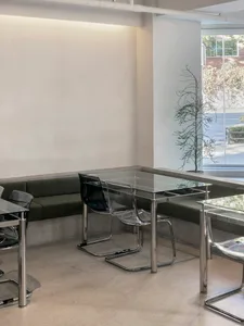 Empty modern dining space with a glass table surrounded by chairs, creating a calm and inviting atmosphere