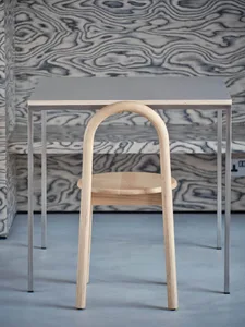A professional office setting with a wooden chair in front of a metal desk, featuring a unique chair design and organized workspace