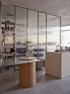 Open kitchen with a wooden island, a vase of flowers, books, and bottles, creating a clean and welcoming atmosphere