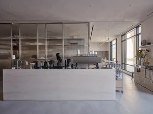 Industrial kitchen with a counter featuring cups, bottles, coffee pots, and bowls, suggesting a functional workspace