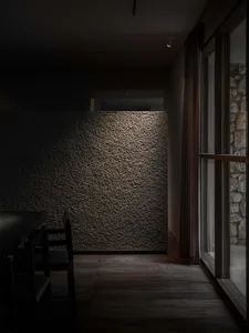 Dining area with a stone wall backdrop, a wooden dining table, and two chairs, creating an elegant and sophisticated atmosphere