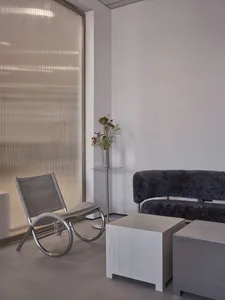 Cozy living area with a sofa, armchair, and table, featuring a vase on a surface between the chairs