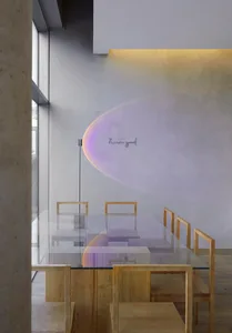 A modern restaurant interior with a large glass dining table surrounded by wooden chairs, bathed in bright natural light