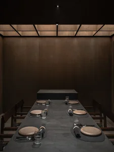 Formal dining area with a long wooden table and chairs, featuring place settings and decorative bowls