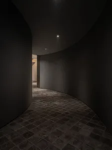 A calm and quiet interior hallway with a curved design, made of concrete, and a door leading to another part of the building