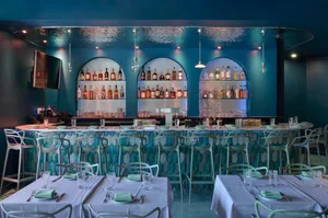 A social bar area with a long wooden counter, chairs, and a welcoming atmosphere