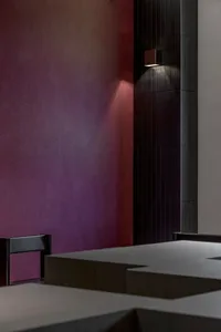 Dining area with a wooden table, two chairs, and a vase, set against a warm red-painted wall