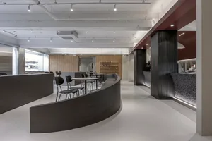 開放式餐廳內部，弧形設計結合木質與金屬元素，設有椅子與餐桌，營造現代而溫馨的氛圍