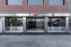 A contemporary building with a metal door and brick facade, set against a bright and sunny background