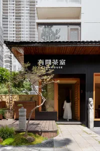 Inviting Asian restaurant with a wooden exterior, black doorway, and potted plants surrounding the entrance