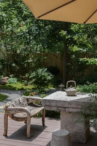 A stone table and chairs in a relaxing outdoor space with a metal vase on the table