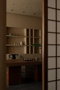 Cozy study space with a wooden desk, chair, and bookshelf, featuring traditional Asian interior design elements and decorative items