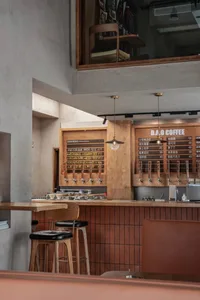 Inviting coffee shop interior with wooden walls and floors, chairs, and a bar counter with multiple cups