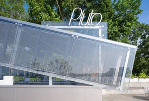 A modern building with a large glass staircase, surrounded by trees in an urban environment