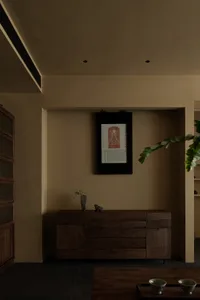 Cozy living area with a wooden cabinet, potted plant, and framed artwork, creating a warm and inviting atmosphere