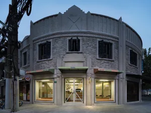 A modern building with a large archway entrance, featuring multiple chairs arranged in a welcoming atmosphere, well-lit by natural light through large windows