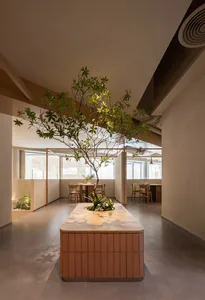 現代餐廳內部，設有大型餐桌、盆栽與水泥牆，營造溫馨氛圍