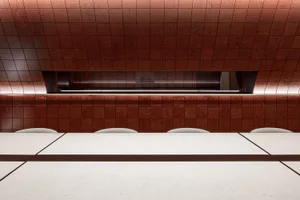 A warm and inviting dining space with a large wooden table surrounded by brown walls and two benches, suggesting a cozy atmosphere for socializing