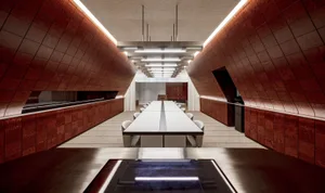 A large dining table surrounded by chairs in a spacious restaurant with wooden floors and walls, creating a warm and inviting atmosphere