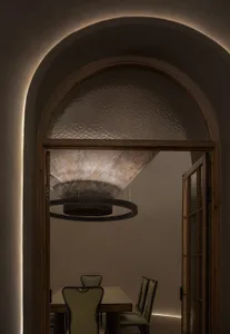 Dimly lit room with two chairs, white and brown walls, and a doorway to another room
