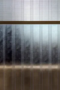 A large glass wall with a reflective metal surface, giving an industrial appearance in a minimalist setting