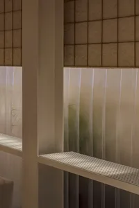 Two modern benches sit in front of a glass wall, surrounded by a minimalist outdoor space