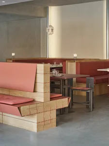 Empty restaurant interior with wooden tables, red accents, and a clean atmosphere