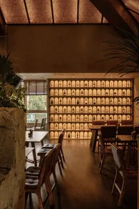Inviting restaurant or bar area with a stone wall display of wine bottles, comfortable seating, and dining tables