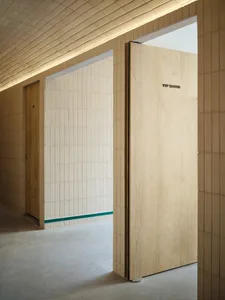 A bright and inviting hallway with open doors to a small room, featuring ceramic tile walls and natural light