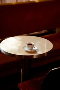An empty coffee shop with a glass table and two chairs, creating a welcoming atmosphere for customers to relax and socialize