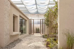 Open living area with glass door to patio, stone and wood flooring, multiple windows and doors, and modern decor