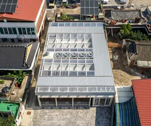 A modern building with a glass skylight on its roof, surrounded by concrete elements, in a contemporary and stylish living environment