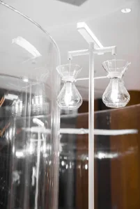 A dimly lit room with two glass vases, one on the left and one centrally positioned, creating a moody atmosphere