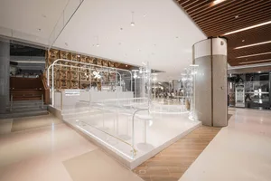 Open modern space with multiple dining tables, chairs, and lights, featuring predominantly white materials and a bright atmosphere