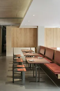 Warm and inviting restaurant interior with wooden walls, multiple dining tables, and comfortable seating options