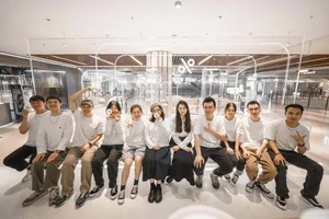 A group of people sitting on wooden benches in a modern indoor space with white walls, creating a relaxed and inviting atmosphere