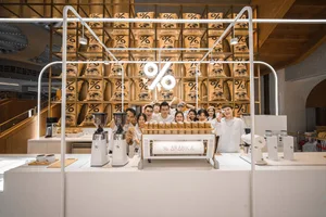 A group of people gather around a coffee shop display featuring various bags of coffee, creating a friendly and inviting atmosphere